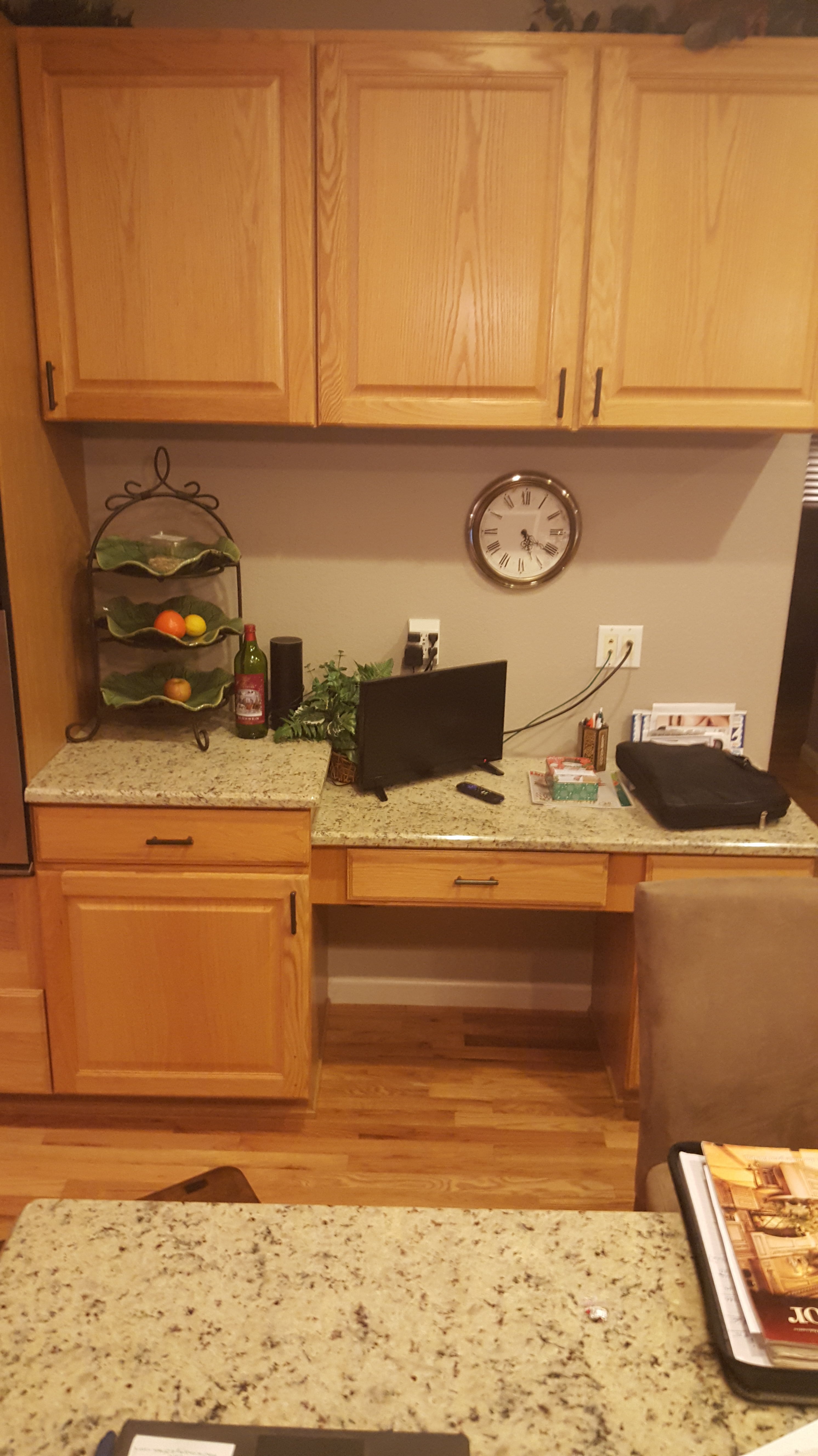 A kitchen with a laptop and a clock on the wall